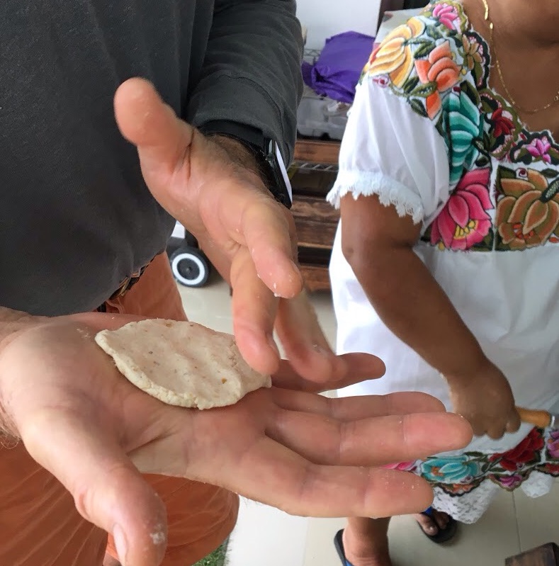 A tortilla being made in the palm of someone's hand in Merida cooking class